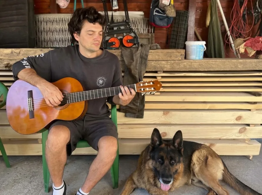 Senid spielt klassische Gitarre, neben ihm liegt sein Schäferhund Romi